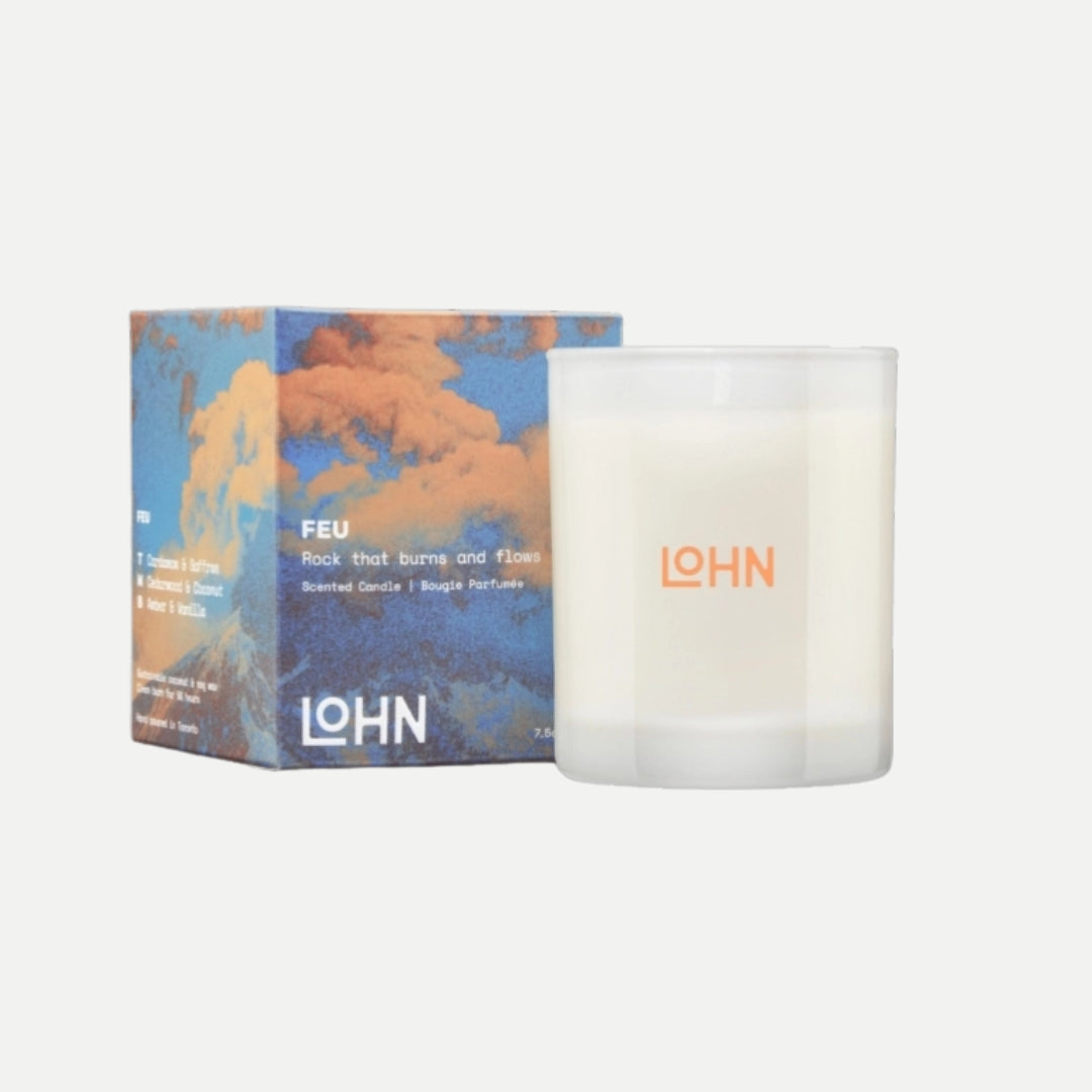 Candle with 'LOHN' branding next to its packaging on a white background